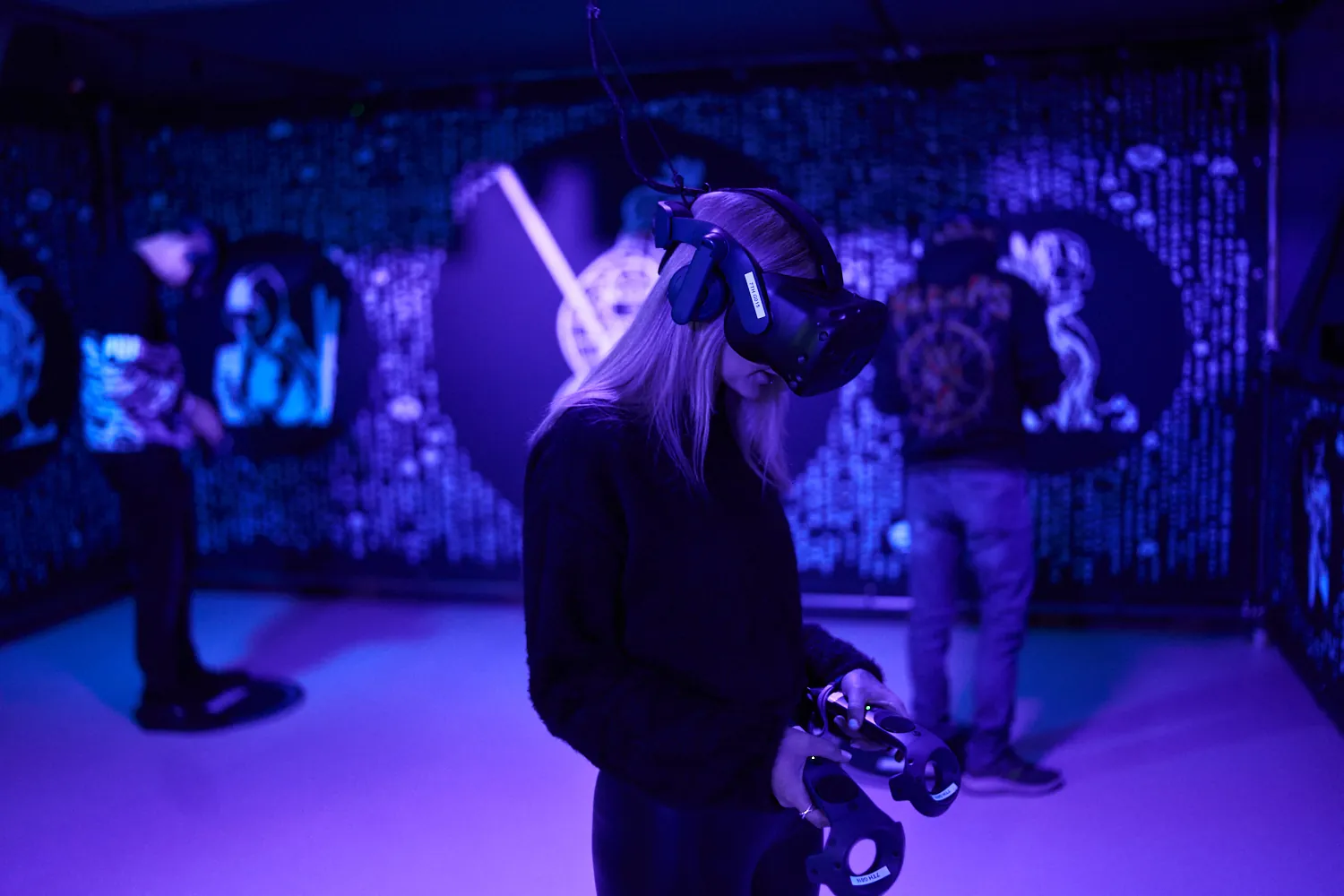 Spieler mit VR-Brillen in einer violett beleuchteten Arena