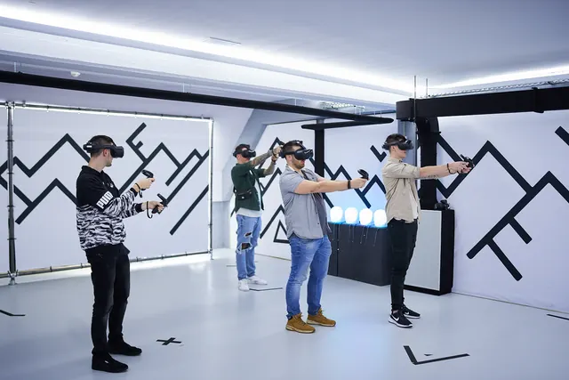 Gruppe mit VR-Brillen und Controllern in einem hellen Spielraum